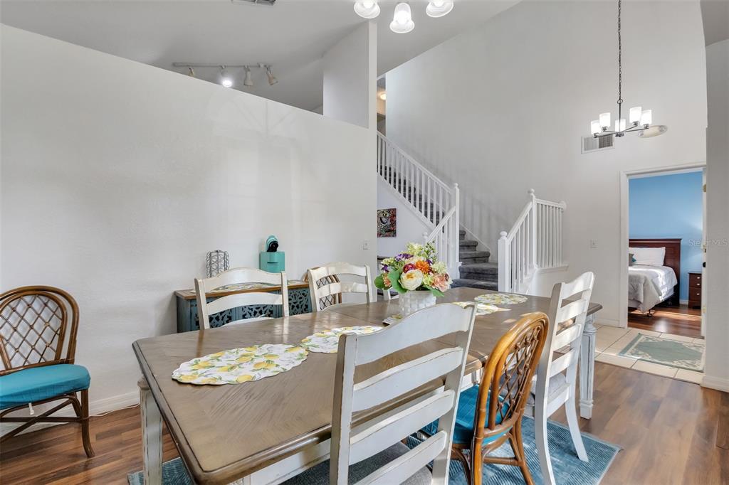 A dining room features a wooden table, mixed seating, and a staircase in the background — 17833 WOODCREST WAY, CLERMONT, FL
