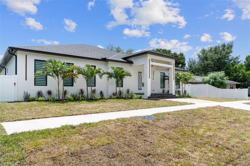 A single-story white house with a covered entryway, dark window shutters, and palm trees — 2914 W WALNUT STREET, TAMPA, FL