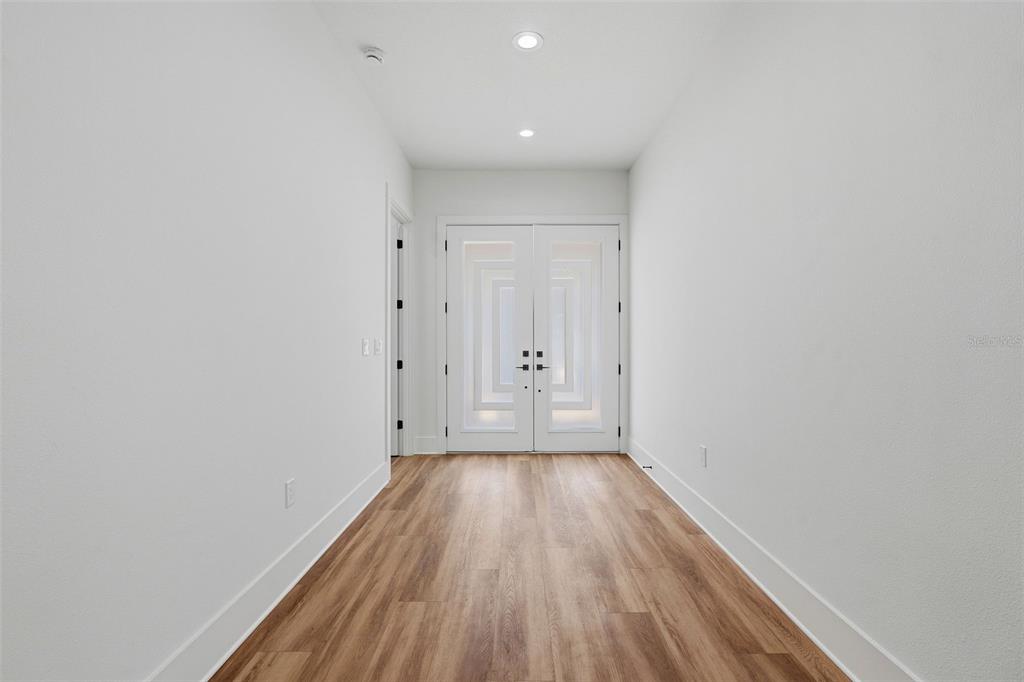 A hallway with light wood-look flooring leads to a set of white double doors — 2914 W WALNUT STREET, TAMPA, FL