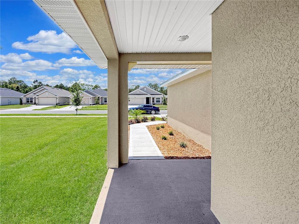 A view from a covered porch looking out toward a suburban street and neighboring houses — 7625 BENT TREE LOOP, ST CLOUD, FL