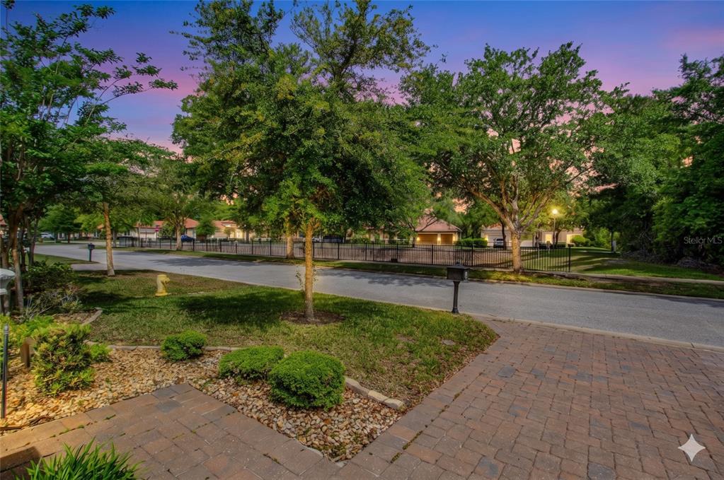 A paved driveway leads to a grassy front yard with trees and a black metal fence — 108 VIA ROMA, ORMOND BEACH, FL