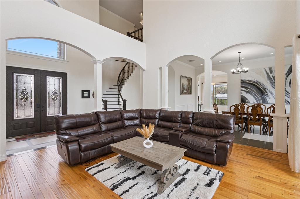 A living room features a large brown sectional, a wooden coffee table, and a curved staircase — 91 WOODLAND DRIVE, HAINES CITY, FL