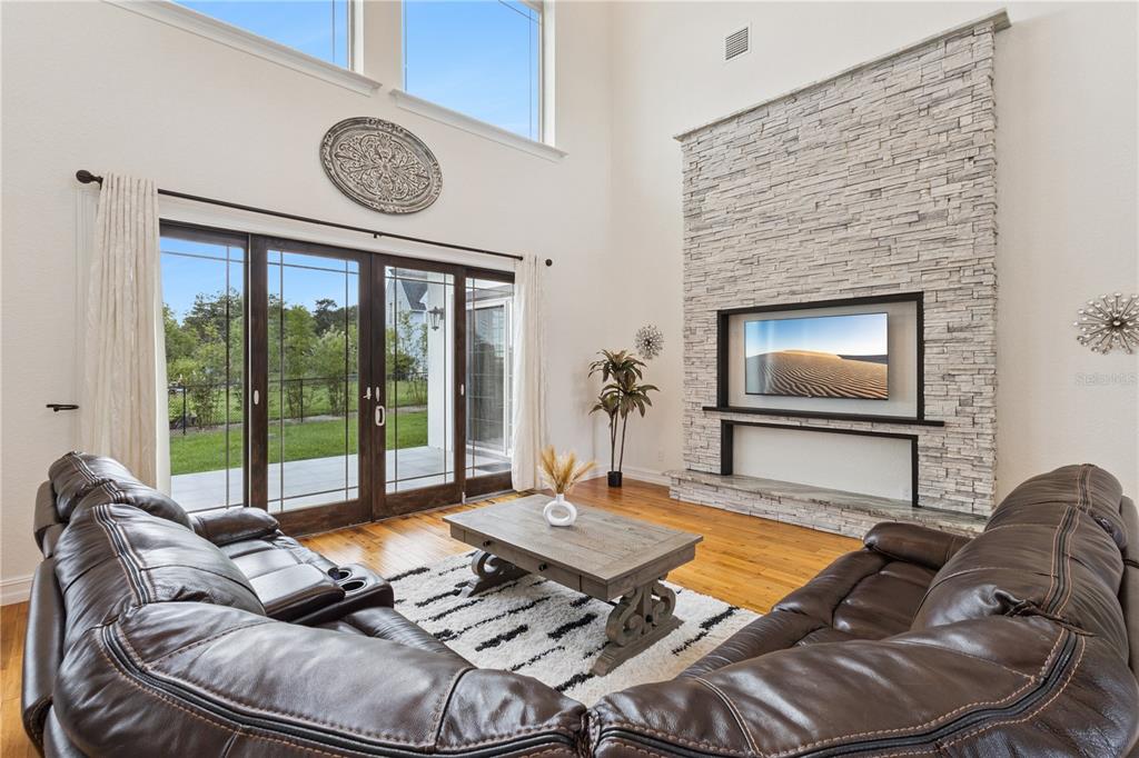 A living room features a stone fireplace, a television, a coffee table, and sliding glass doors — 91 WOODLAND DRIVE, HAINES CITY, FL