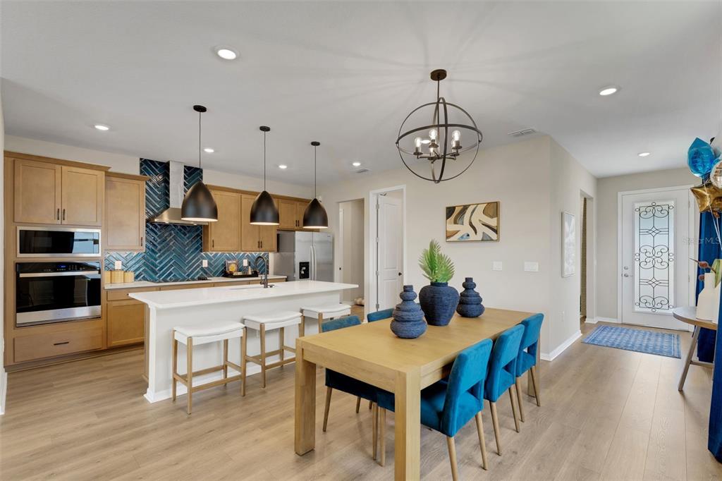 A kitchen and dining area with light wood cabinets, blue herringbone backsplash, and blue chairs — 17078 SQUIRREL BRANCH LANE, ALVA, FL