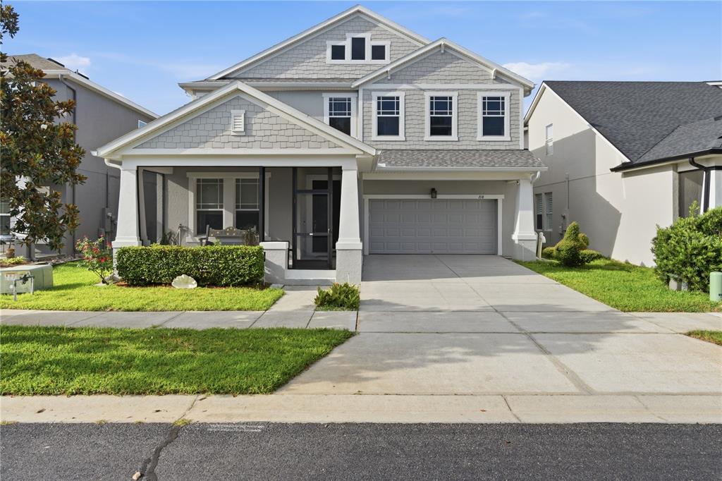 A two-story house with a gray shingled exterior, a screened front porch, and a garage — 718 BAREFOOT BAY LOOP, GROVELAND, FL