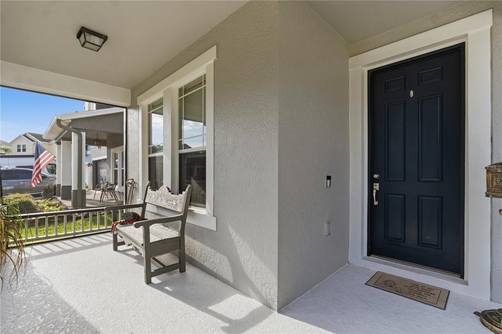 A covered front porch features a gray bench, a dark blue door, and a doormat — 718 BAREFOOT BAY LOOP, GROVELAND, FL