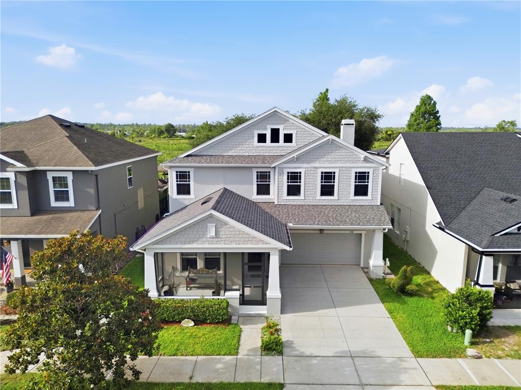 An aerial view shows a two-story house with a front porch and a concrete driveway — 718 BAREFOOT BAY LOOP, GROVELAND, FL