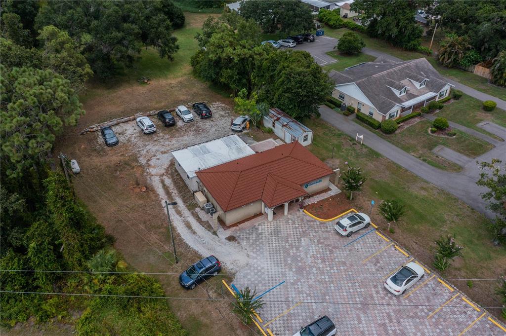 An aerial view shows a commercial building with a tiled roof, parking lot, and surrounding trees — 10508 GIBSONTON DR, RIVERVIEW, FL