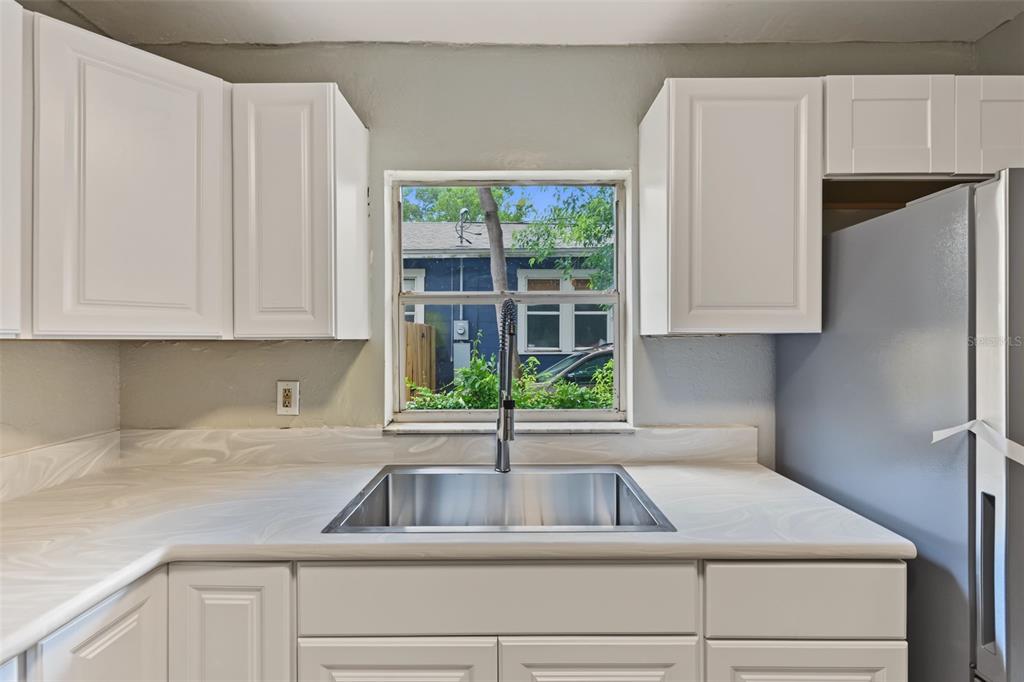 A kitchen sink area features white cabinets, a marble-patterned countertop, and a window view — 6317 N CENTRAL AVENUE, TAMPA, FL
