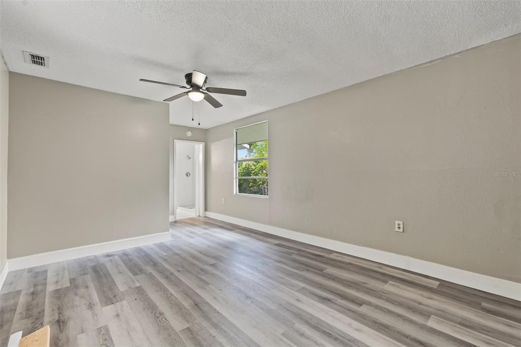 An empty bedroom features light gray walls, wood-look laminate flooring, and a ceiling fan — 6317 N CENTRAL AVENUE, TAMPA, FL