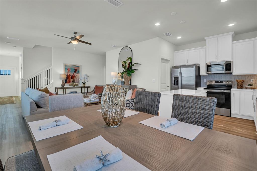 A dining area with a wooden table overlooks an open-concept living room and kitchen — 13992 EMERALD FIELDS DRIVE Lot 24, HUDSON, FL