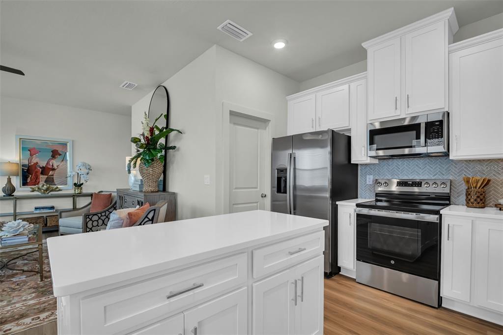 A modern kitchen features white cabinetry, stainless steel appliances, and a central island — 13992 EMERALD FIELDS DRIVE Lot 24, HUDSON, FL