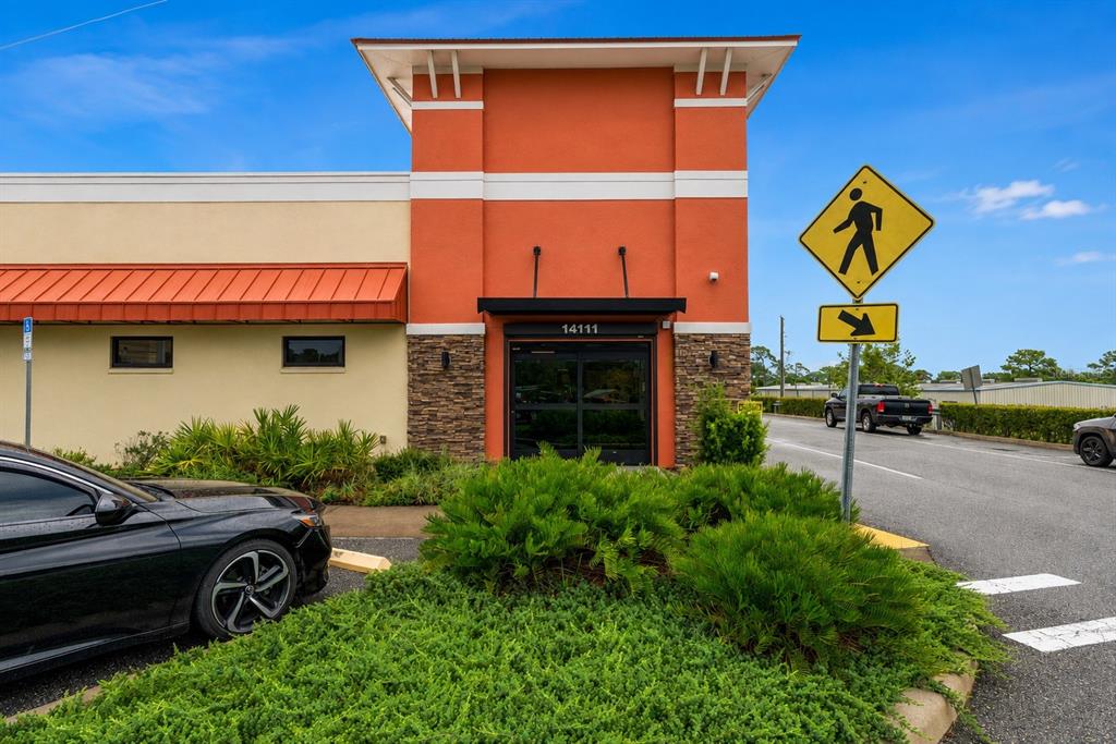 The exterior of a commercial building features an orange facade, a stone base, and a crosswalk — 14111 CORTEZ BOULEVARD, BROOKSVILLE, FL