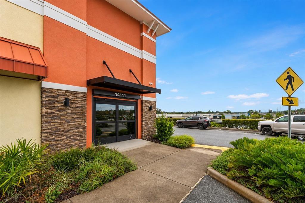 The exterior of a commercial building features an orange facade, stone accents, and a glass entrance — 14111 CORTEZ BOULEVARD, BROOKSVILLE, FL
