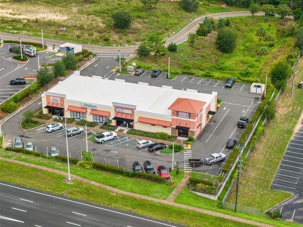 An aerial view shows a commercial strip mall with a parking lot and surrounding landscaping — 14111 CORTEZ BOULEVARD, BROOKSVILLE, FL