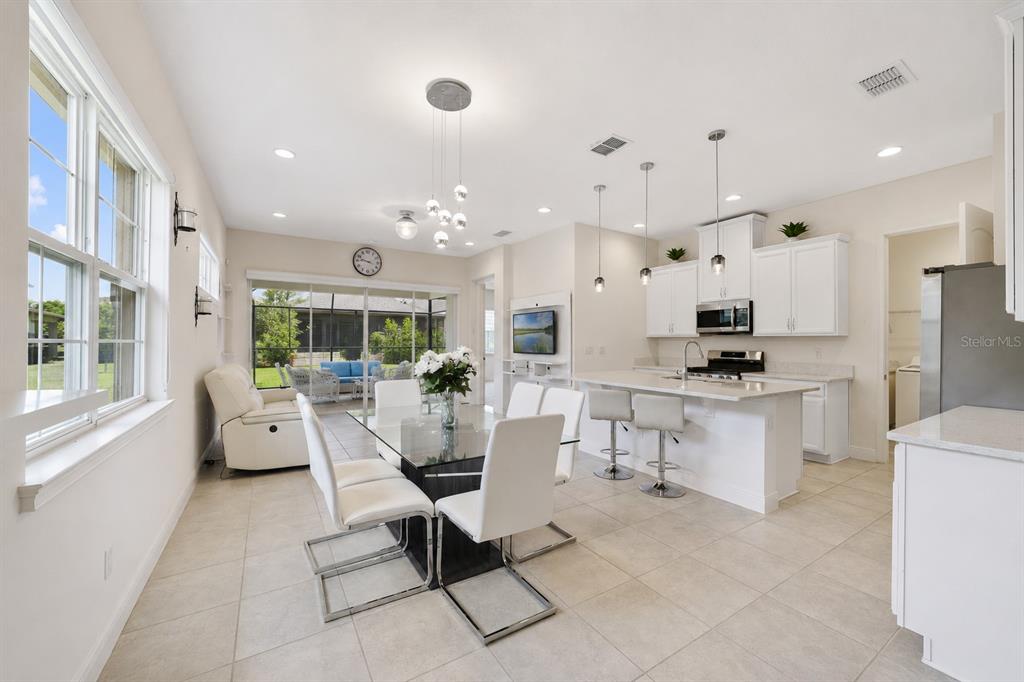 A bright open-concept kitchen and dining area with white cabinetry, tile floors, and glass doors — 2516 DATURA LOOP, ST CLOUD, FL