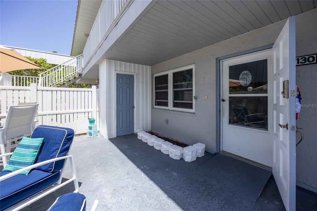 A patio area features a blue door, a white front door, and outdoor furniture — 6777 WINKLER ROAD UNIT 130, FORT MYERS, FL