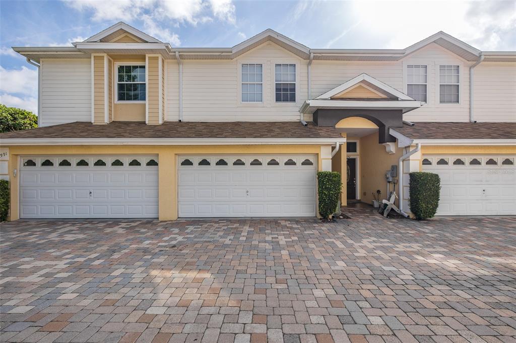A two-story townhouse exterior features a paved driveway, three garage doors, and a recessed entryway — 2989 ESTANCIA PLACE, CLEARWATER, FL