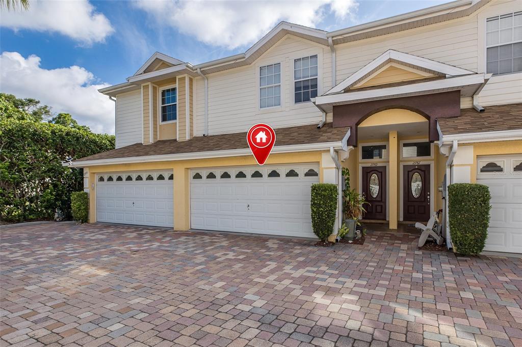 A two-story townhouse exterior features a paved driveway, two garage doors, and two front entrances — 2989 ESTANCIA PLACE, CLEARWATER, FL