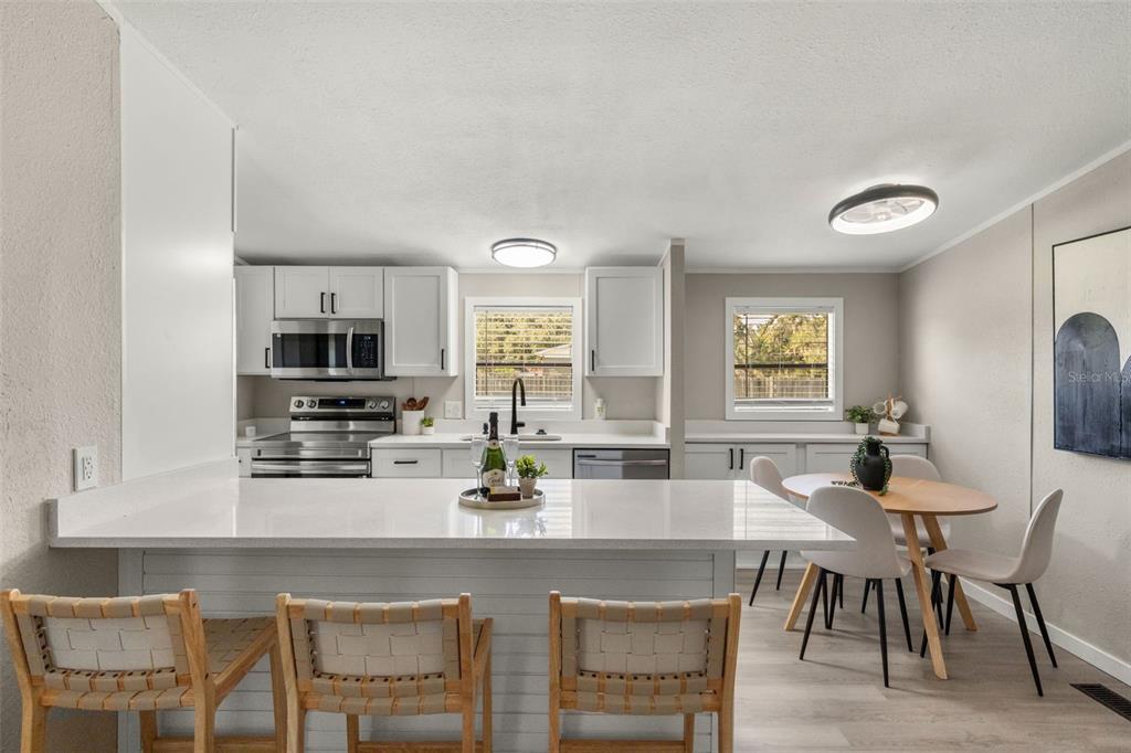 A kitchen with white cabinets, quartz countertops, a breakfast bar, and a dining area — 8110 TOM COSTINE ROAD, LAKELAND, FL