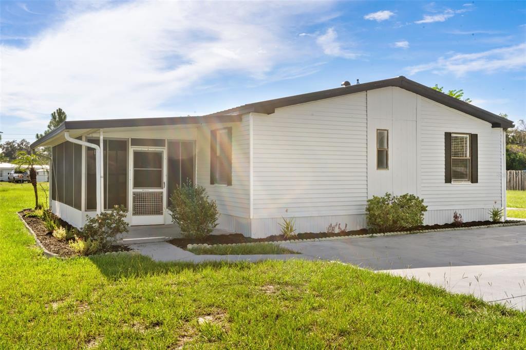 A white manufactured home features a screened-in porch and a concrete driveway — 8110 TOM COSTINE ROAD, LAKELAND, FL
