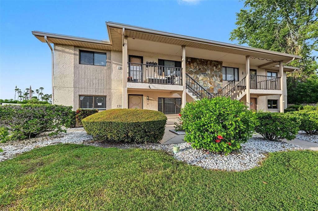 A two-story apartment building with a stone facade, exterior staircases, and landscaped front yard — 9930 EAGLES POINT CIRCLE UNIT 1, PORT RICHEY, FL