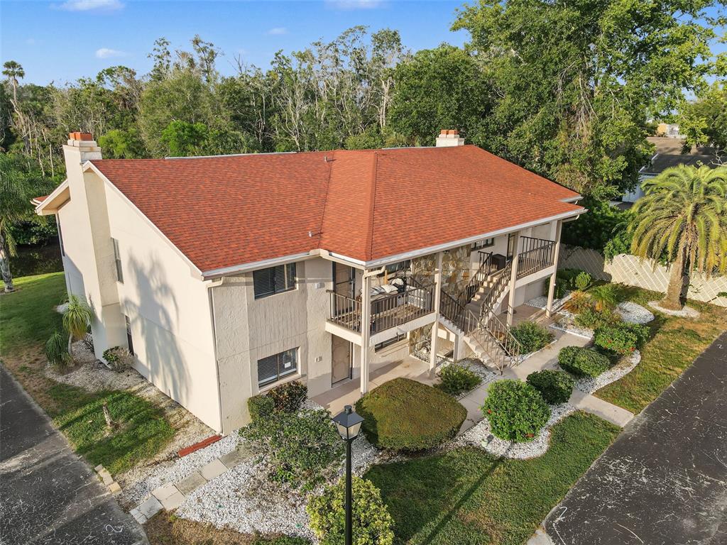 An aerial view of a two-story apartment building with a red shingled roof and balconies — 9930 EAGLES POINT CIRCLE UNIT 1, PORT RICHEY, FL