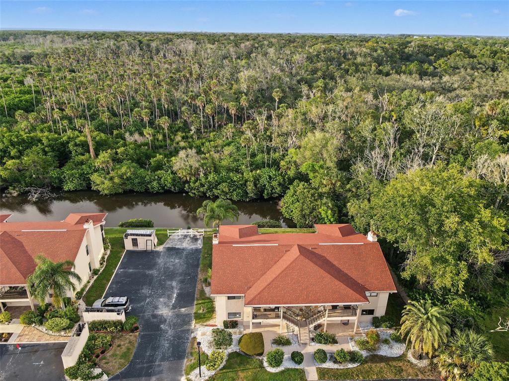 An aerial view shows a house with a red roof, a driveway, and a backyard waterway — 9930 EAGLES POINT CIRCLE UNIT 1, PORT RICHEY, FL