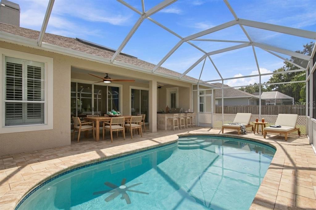 A tan single-story house with a blue front door and a circular stone garden bed — 928 OAKVIEW ROAD, TARPON SPRINGS, FL