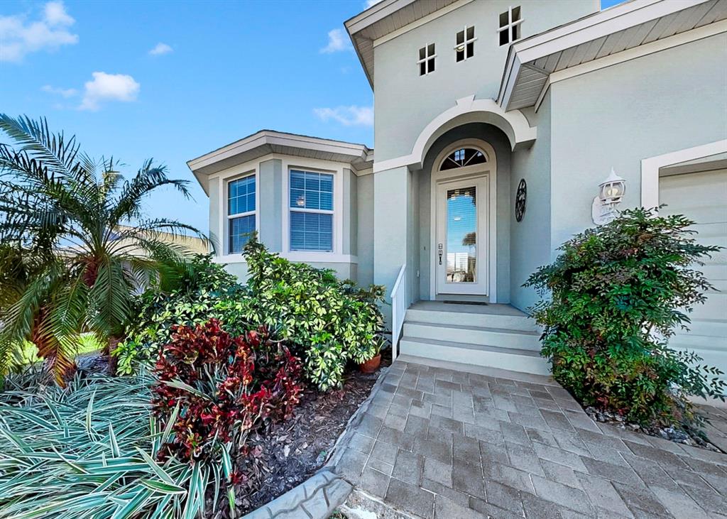 The exterior of a light-colored house features a paved walkway leading to an arched entryway — 916 SPINDLE PALM WAY, APOLLO BEACH, FL
