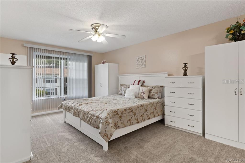A bedroom features a white bed frame, matching dressers, a ceiling fan, and beige carpet — 2400 FOREST DRIVE UNIT 221, INVERNESS, FL