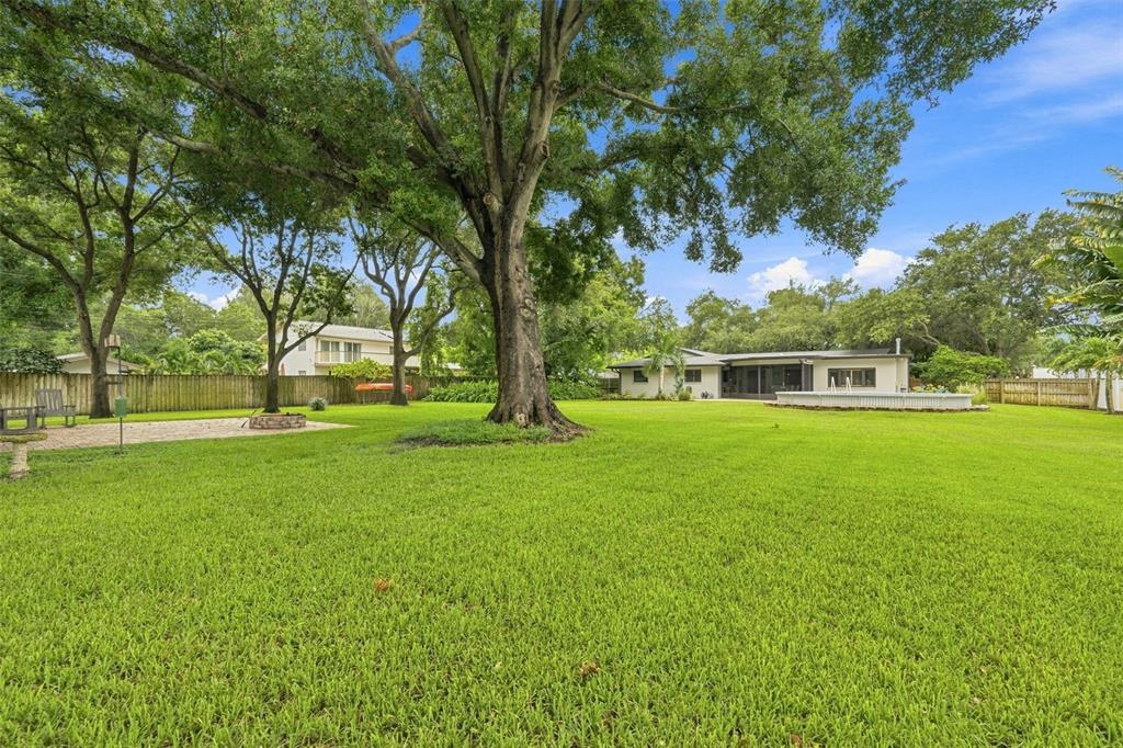 A large, grassy backyard features mature trees, a fire pit area, and an above-ground pool — 13123 108TH AVENUE, LARGO, FL