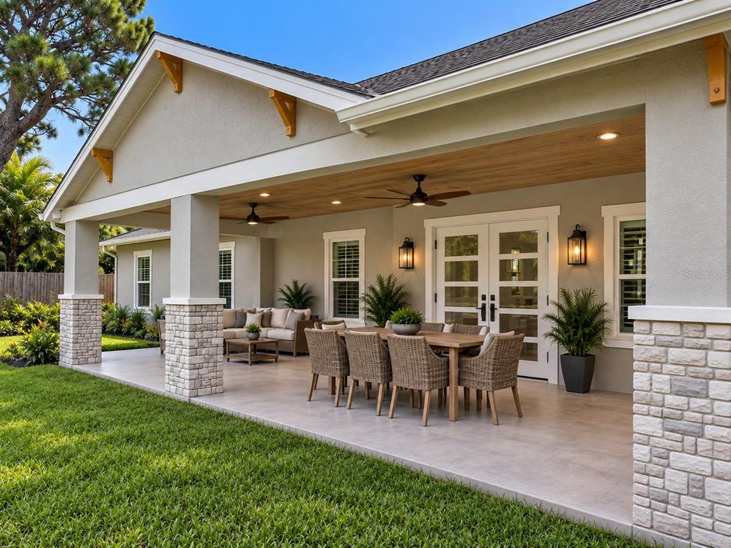 A covered patio features a dining set, lounge furniture, stone columns, and a wood-paneled ceiling — 6941 10TH AVENUE N, ST PETERSBURG, FL
