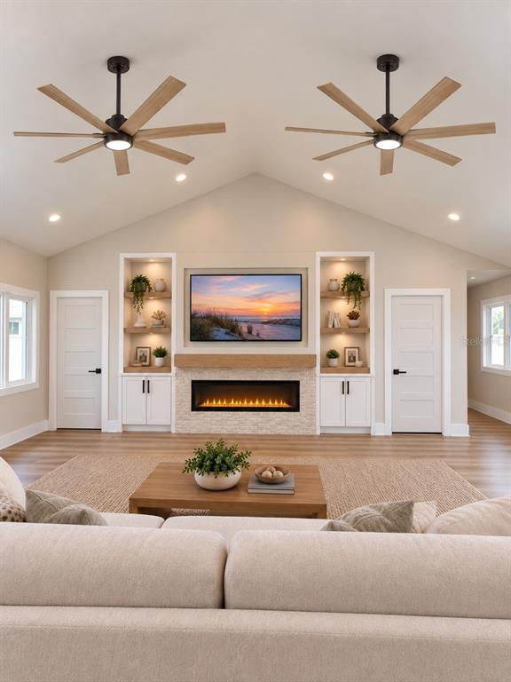 This living room features a vaulted ceiling, dual ceiling fans, a fireplace, and built-in shelving — 6941 10TH AVENUE N, ST PETERSBURG, FL