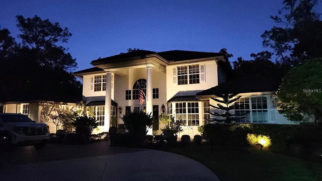 A two-story house with white columns and an American flag at night — 3171 DICK WILSON DRIVE, SARASOTA, FL
