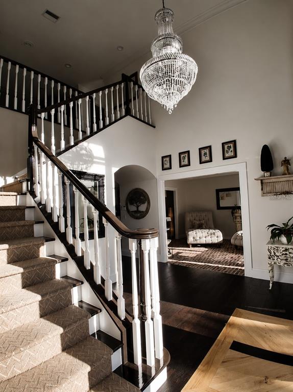 A grand foyer features a crystal chandelier, a carpeted staircase, and dark hardwood flooring — 3171 DICK WILSON DRIVE, SARASOTA, FL