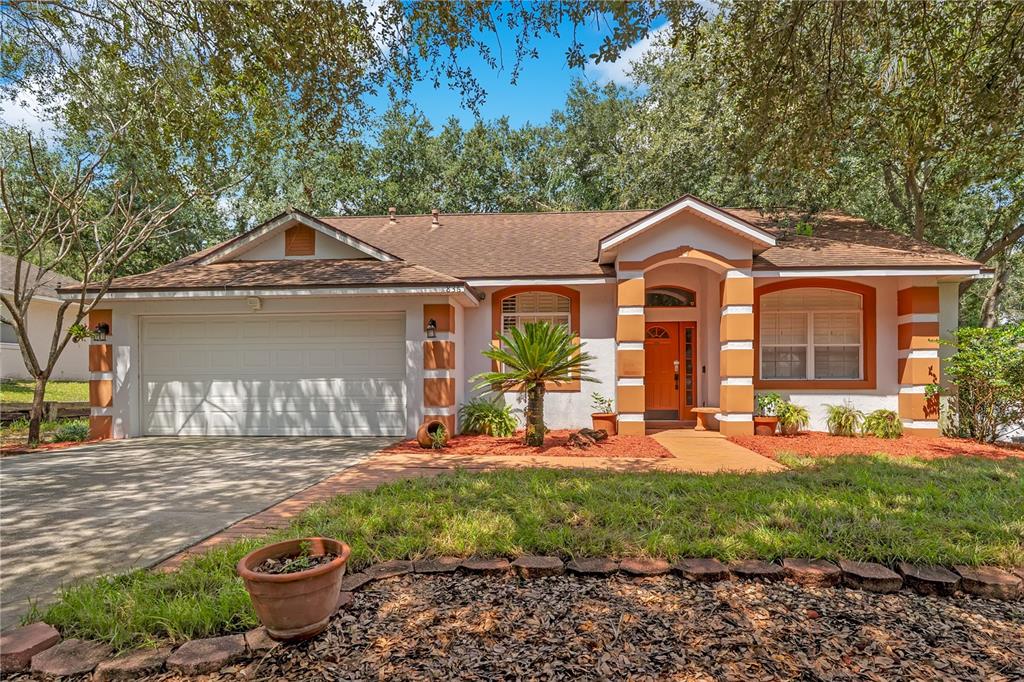 A single-story house with a two-car garage, orange trim, and a landscaped front yard — 836 ELM FOREST DRIVE, MINNEOLA, FL