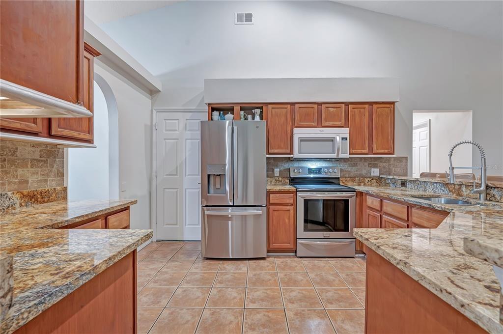 A single-story house with a white stucco facade, orange trim, and a two-car garage — 836 ELM FOREST DRIVE, MINNEOLA, FL