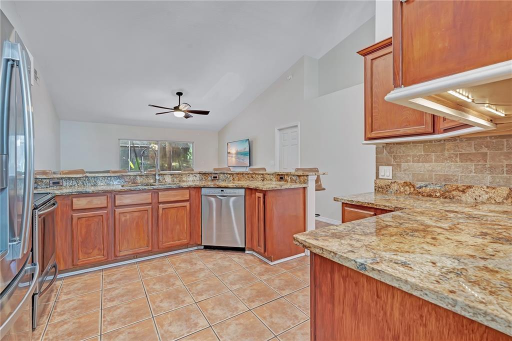 A kitchen with wood cabinets, granite countertops, stainless steel appliances, and tile flooring — 836 ELM FOREST DRIVE, MINNEOLA, FL