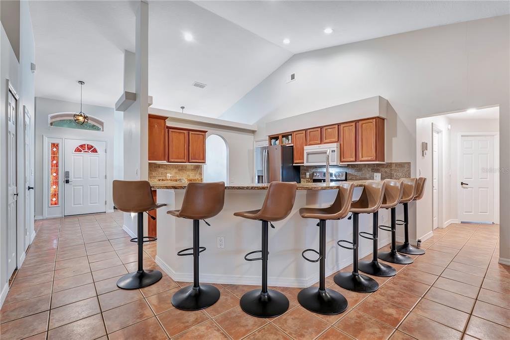 A kitchen with wood cabinets, granite countertops, stainless steel appliances, and tile flooring — 836 ELM FOREST DRIVE, MINNEOLA, FL