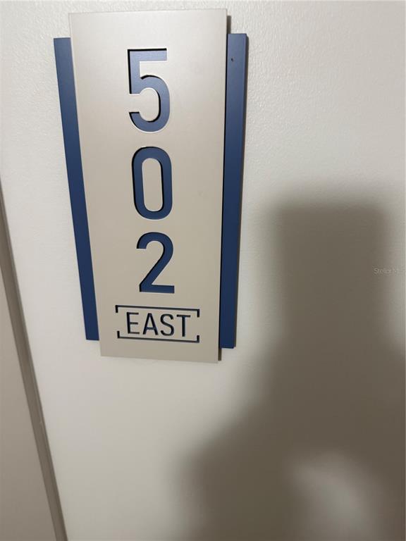 A wall-mounted sign displays the number 502 and the word EAST in dark blue lettering — 1 KEY CAPRI UNIT 502E, TREASURE ISLAND, FL