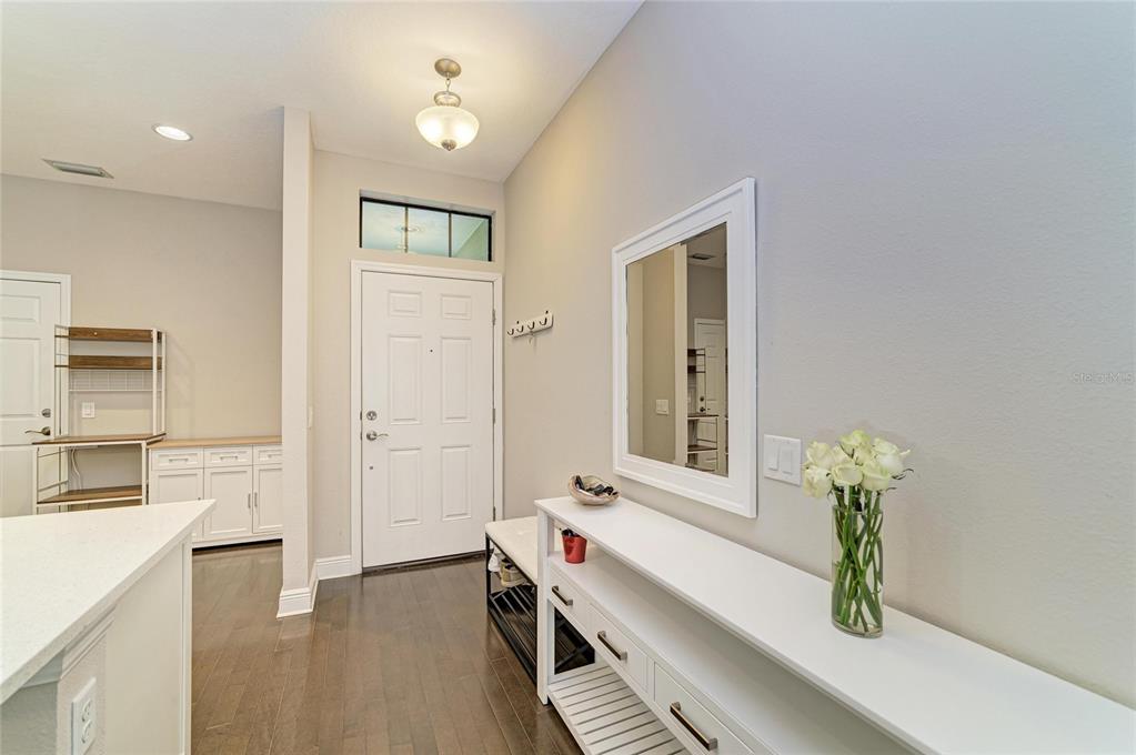 An entryway features a white console table, a mirror, a shoe bench, and dark wood flooring — 4991 OARSMAN COURT, SARASOTA, FL