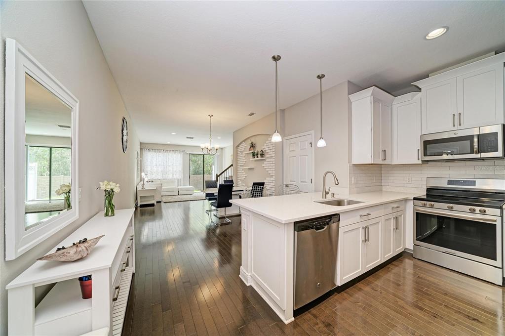 A kitchen with white cabinets and stainless steel appliances opens into a dining and living area — 4991 OARSMAN COURT, SARASOTA, FL