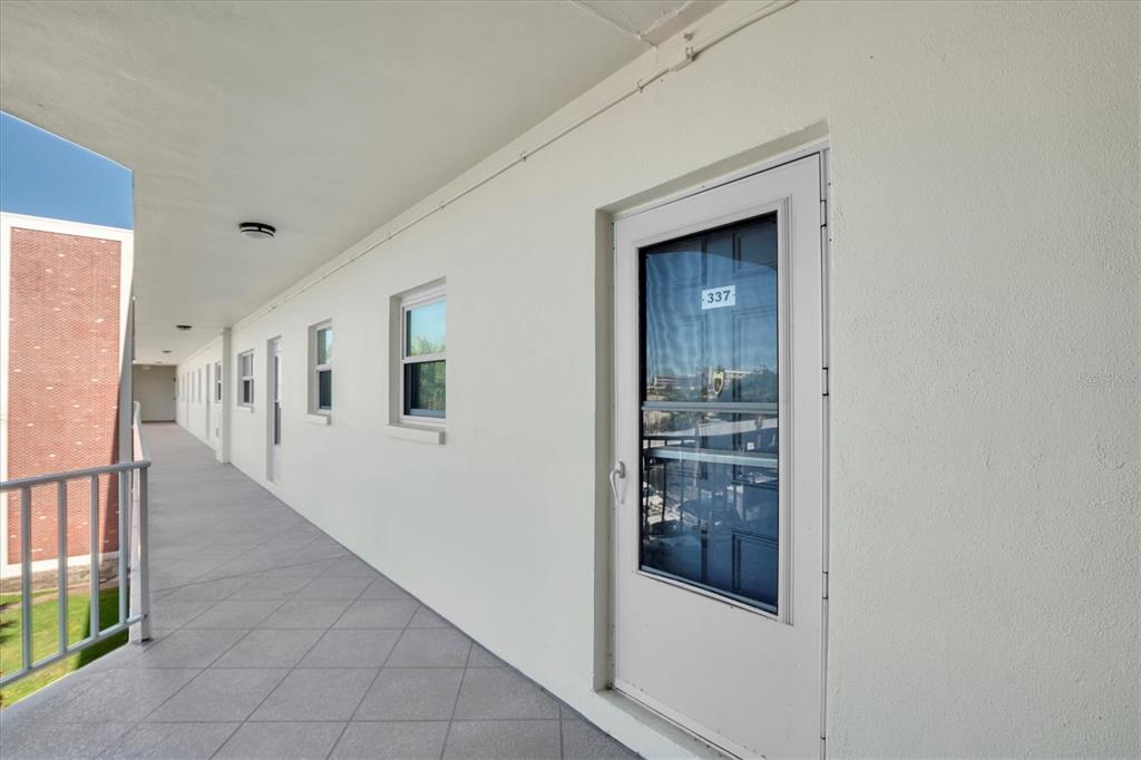An exterior walkway with white walls, windows, and a door labeled 337 — 5575 GULF BOULEVARD UNIT 337, ST PETE BEACH, FL
