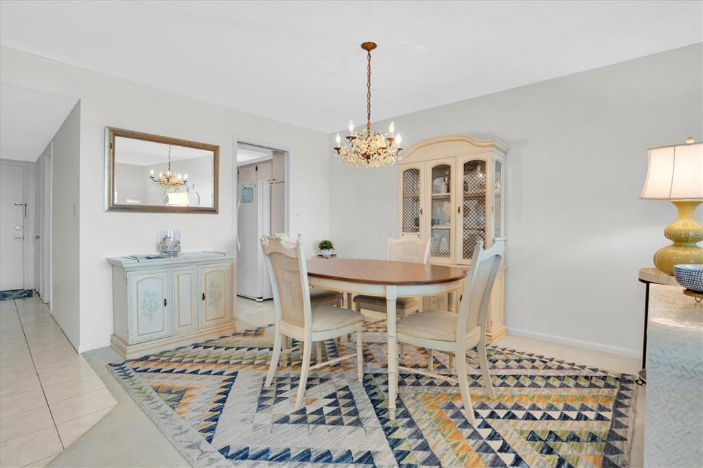 A dining room features a wooden table, chairs, a hutch, and a patterned area rug — 5575 GULF BOULEVARD UNIT 337, ST PETE BEACH, FL