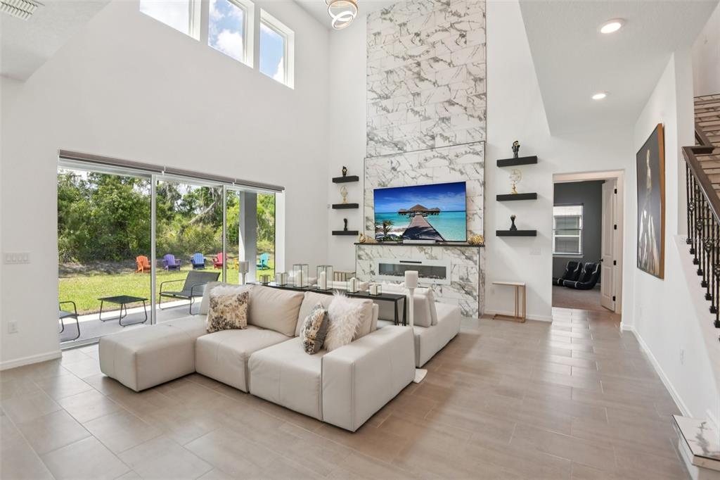 A bright living room features a marble fireplace, high ceilings, and a large sectional sofa — 11473 OWASEE TRAILS PLACE, RIVERVIEW, FL