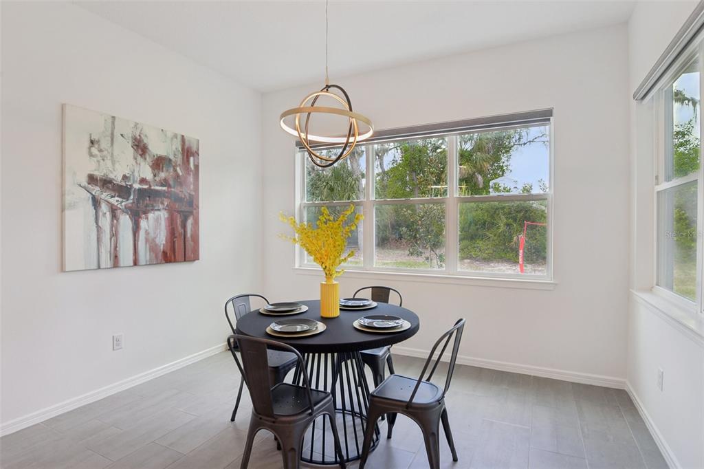 A dining area features a round black table, metal chairs, and a modern pendant light — 11473 OWASEE TRAILS PLACE, RIVERVIEW, FL