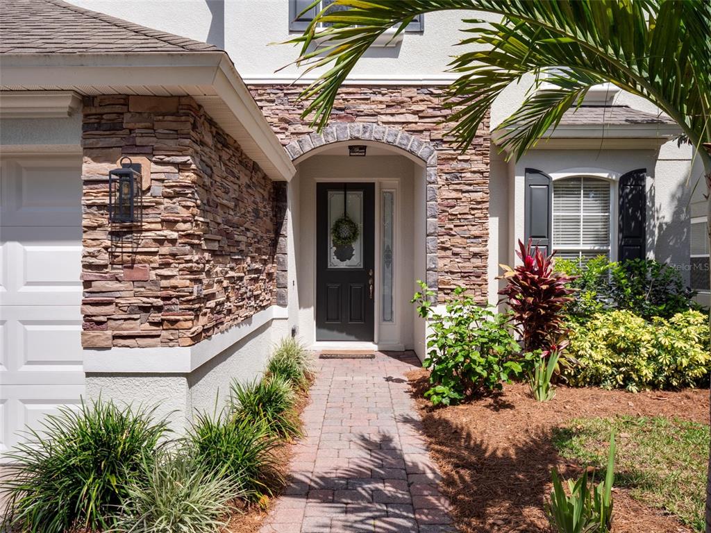 A stone-accented house exterior features a brick walkway leading to a dark front door — 13156 HATHERTON CIRCLE, ORLANDO, FL