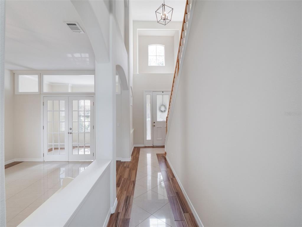 A bright entryway features a high ceiling, a staircase, and a mix of tile flooring — 13156 HATHERTON CIRCLE, ORLANDO, FL