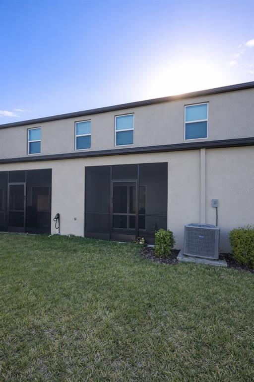 The exterior of a two-story building features a screened-in patio and an air conditioning unit — 12420 CRYSTAL JADE WAY, PARRISH, FL